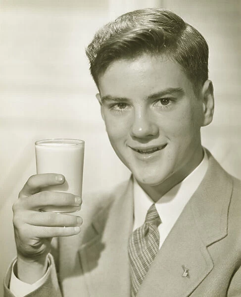 Young man holding glass of milk, (B&W), portrait