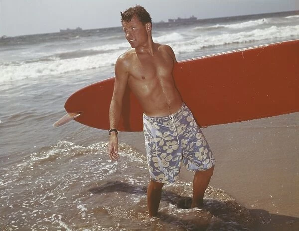 Young man holding surfboard on beach