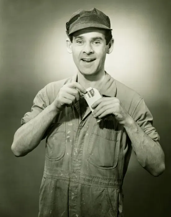 Framed Print : Young man in overalls showing card in studio, (B&W), portrait Framed Print : Young man in overalls showing card in studio, (B&W), portrait