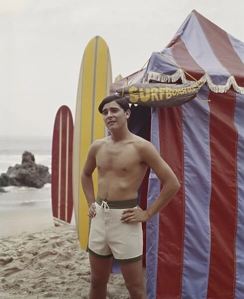 Young man standing beside tent on beach, portrait