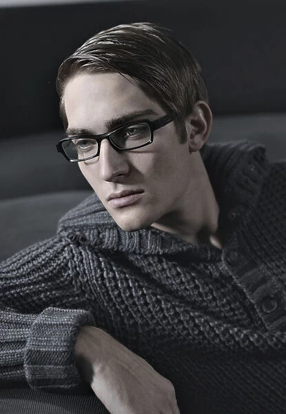Young man wearing glasses sitting on a sofa