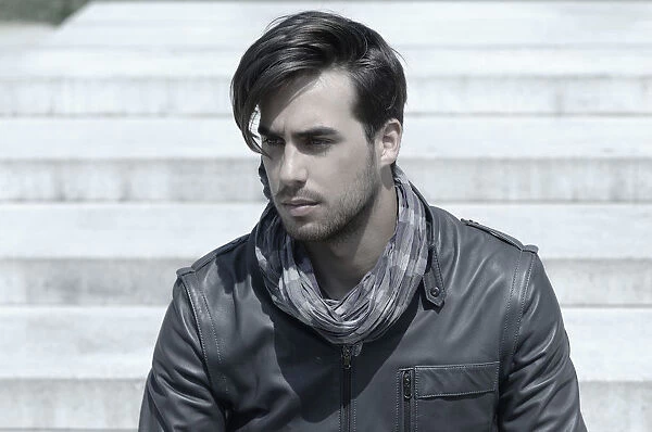 Young man wearing a leather jacket in front of an open staircase, portrait