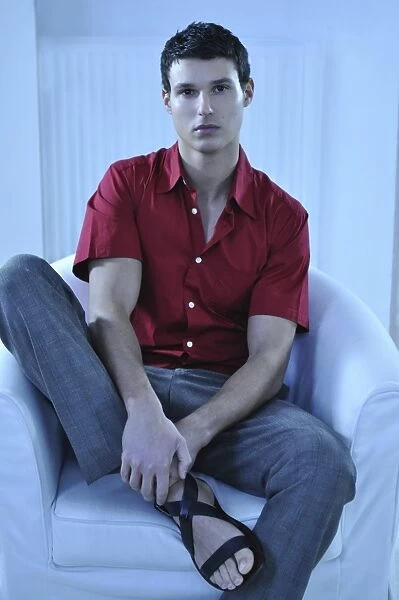 Young man wearing a red shirt sitting in an armchair