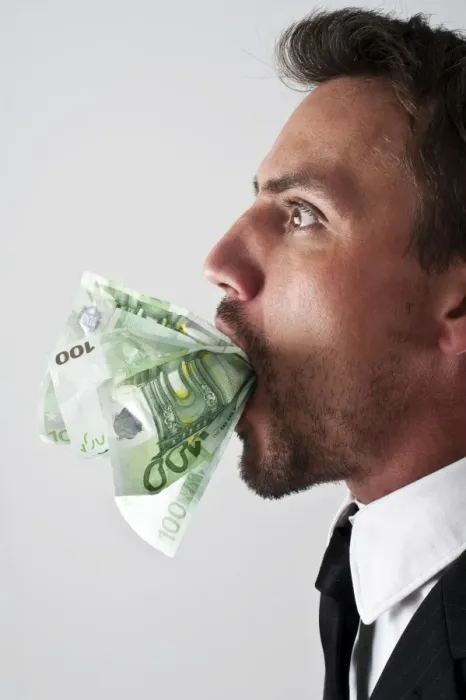 Framed Print : Young man wearing a suit with 100-euro notes stuffed into his mouth Framed Print : Young man wearing a suit with 100-euro notes stuffed into his mouth
