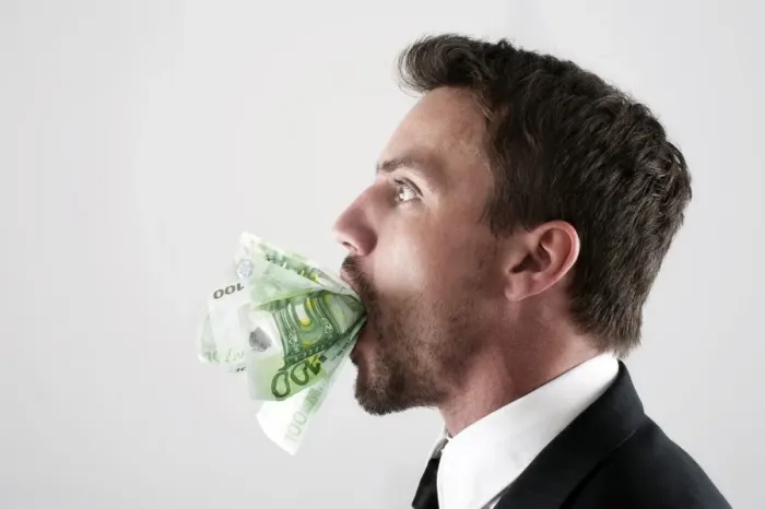 Framed Print : Young man wearing a suit with 100-euro notes stuffed into his mouth Framed Print : Young man wearing a suit with 100-euro notes stuffed into his mouth