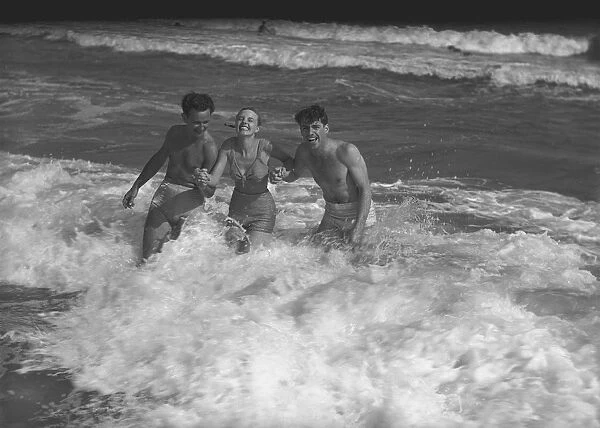 Two young man and woman playing in wave, (B&W)