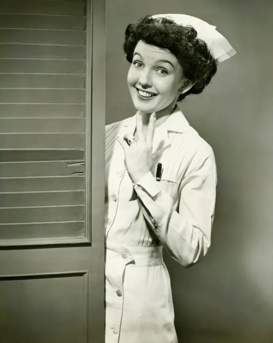 Framed Print : Young nurse smiling by open door, (B&W) Framed Print : Young nurse smiling by open door, (B&W)