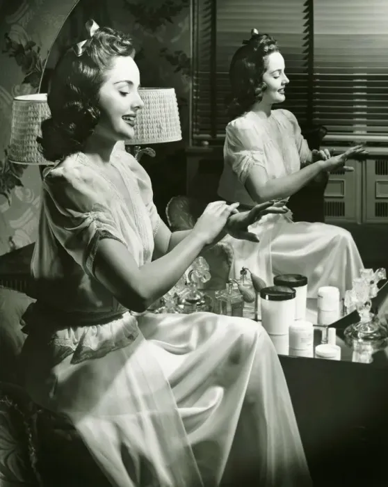 Framed Print : Young woman applying cream in front of mirror, (B&W) Framed Print : Young woman applying cream in front of mirror, (B&W)