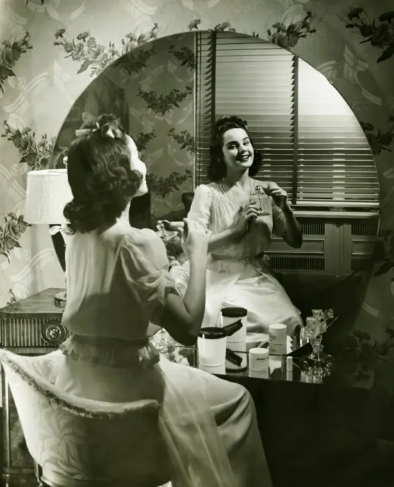 Framed Print : Young woman applying cream in front of mirror, (B&W) Framed Print : Young woman applying cream in front of mirror, (B&W)