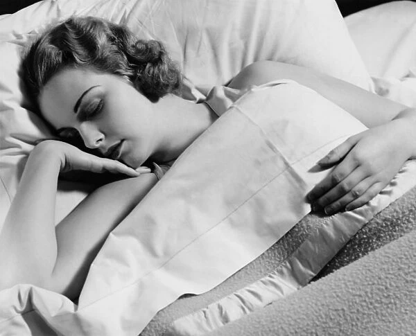 Young woman asleep in bed, (B&W), close-up