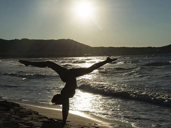 Young woman doing gymnastics on the beach, backlight, Corsica, France