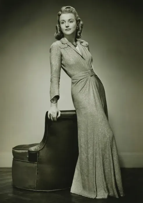 Framed Print : Young woman in evening dress leaning against chair, (B&W) Framed Print : Young woman in evening dress leaning against chair, (B&W)