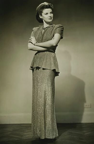 Young woman in fashionable dress standing in studio, (B&W)
