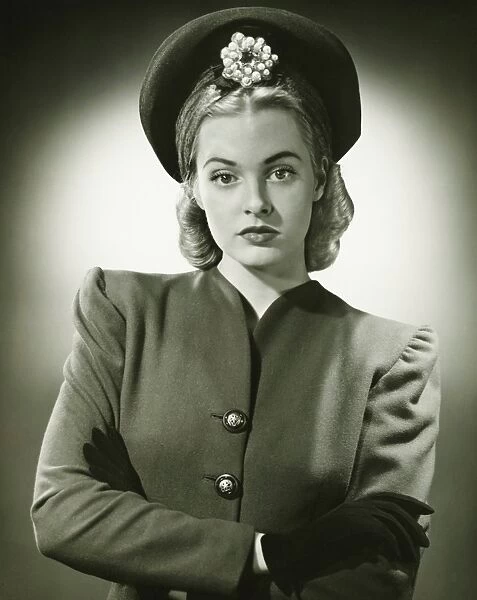 Young woman in fashionable suit and hat in studio, (B&W), portrait