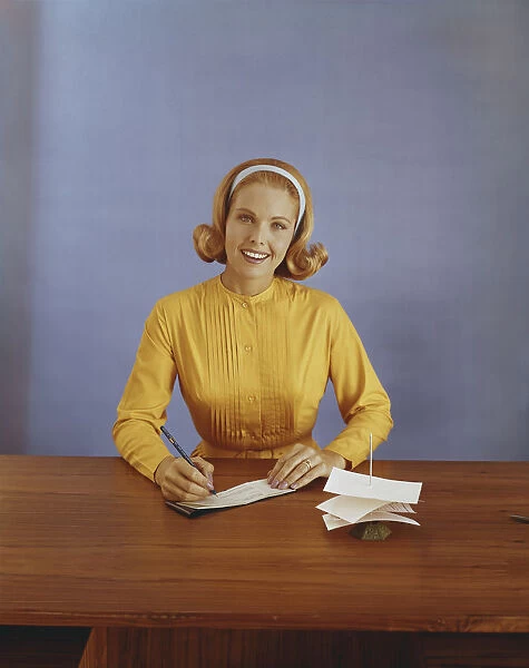 Young woman filling out bank slip, smiling, portrait