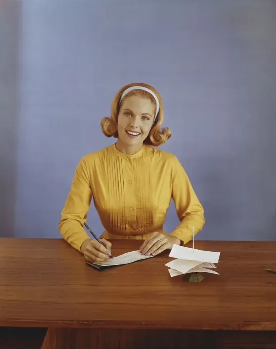 Framed Print : Young woman filling out bank slip, smiling, portrait Framed Print : Young woman filling out bank slip, smiling, portrait