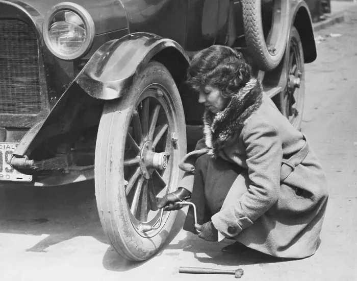 Framed Print : Young Woman Fixing Flat On Old Car Framed Print : Young Woman Fixing Flat On Old Car