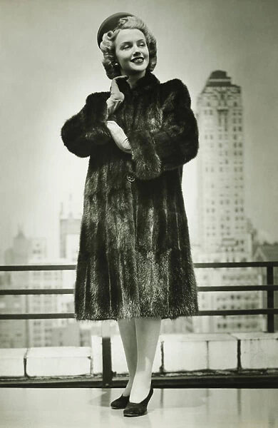 Young woman in fur coat standing outdoors, (B&W)