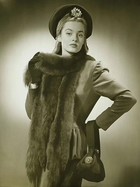 Young woman with fur collar posing in studio, (B&W), portrait