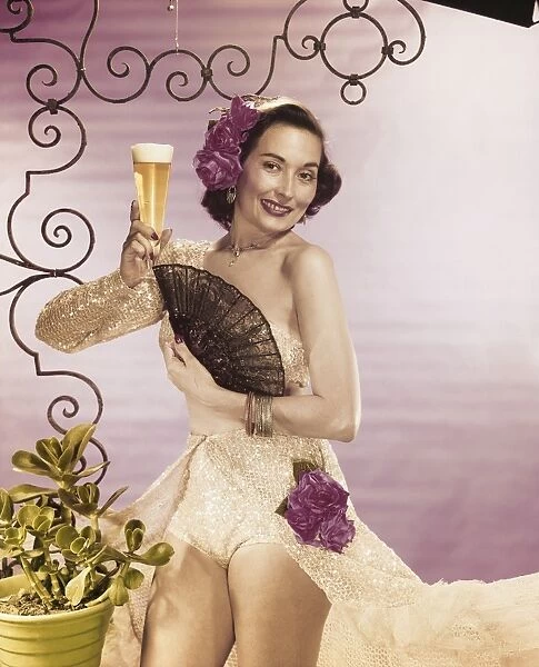 Young woman holding beer glass with folding fan, smiling, portrait