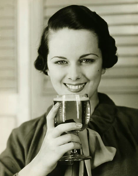 Young woman holding glass of beer, (B&W), portrait