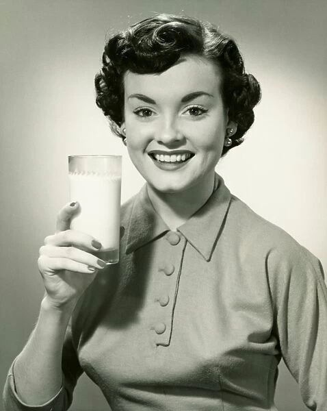 Young woman holding glass of milk, (B&W), portrait