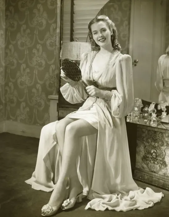 Framed Print : Young woman holding mirror, sitting at dresser, (B&W) Framed Print : Young woman holding mirror, sitting at dresser, (B&W)