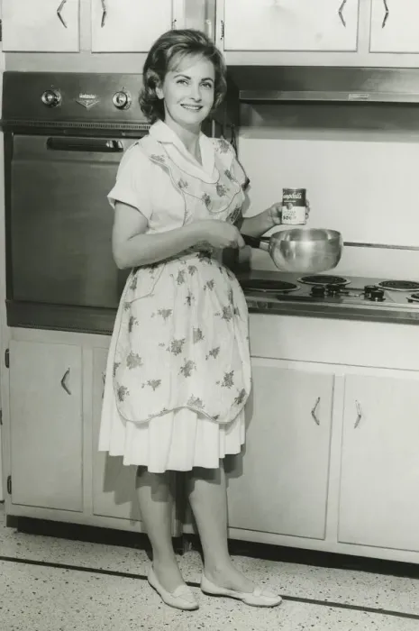 Framed Print : Young woman holding can of soup and pot in kitchen, (B&W) Framed Print : Young woman holding can of soup and pot in kitchen, (B&W)