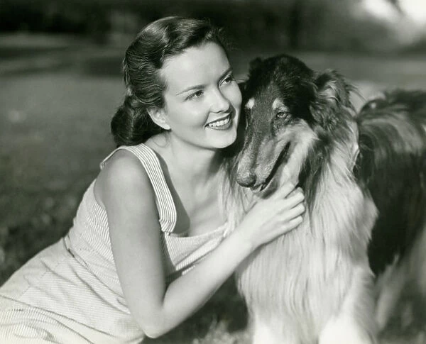 Young woman hugging Collie in park
