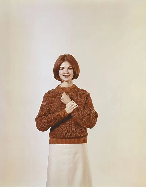 Young woman in jumper standing against white background