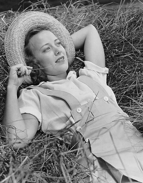 Young woman laying in hay thinking