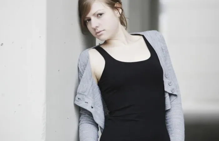 Framed Print : Young woman leaning against a wall