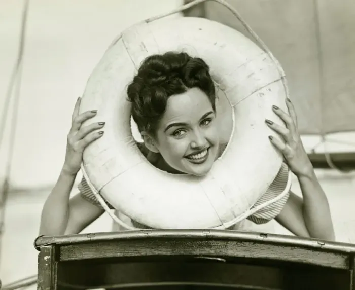 Framed Print : Young woman looking through lifebelt, smiling, (B&W)