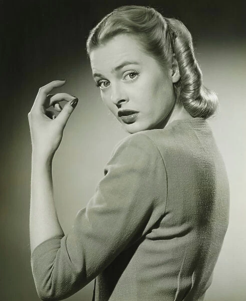 Young woman looking over shoulder, (B&W), portrait