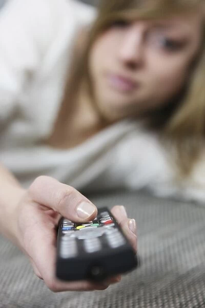 Young woman lying down with remote in her hand