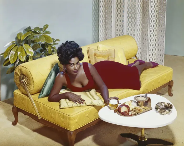 Framed Print : Young woman lying on sofa with snacks on table, portrait Framed Print : Young woman lying on sofa with snacks on table, portrait