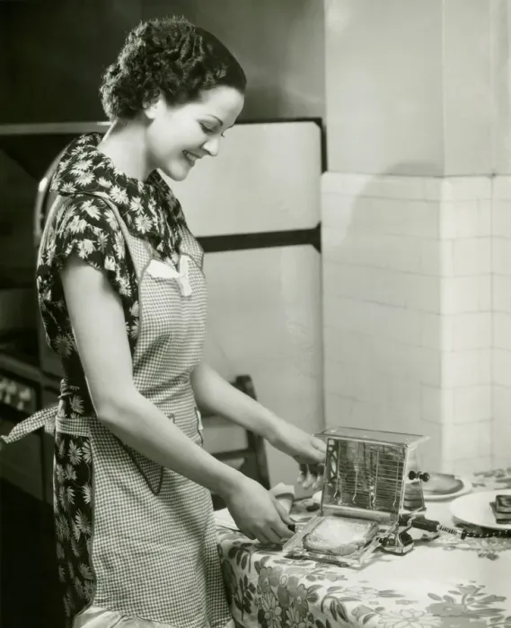 Framed Print : Young woman making slice of toast, (B&W), portrait Framed Print : Young woman making slice of toast, (B&W), portrait