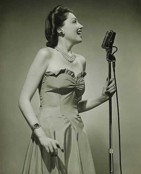 Young woman at microphone, singing, (B&W)