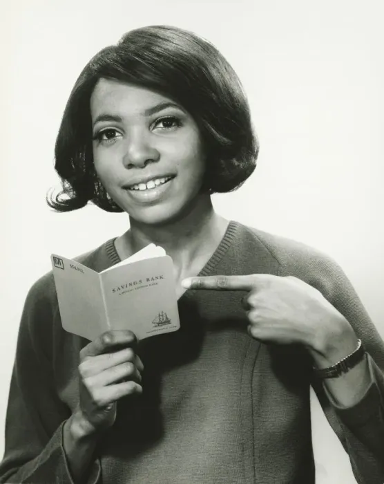 Framed Print : Young woman pointing at bank book, smiling, (B&W), portrait Framed Print : Young woman pointing at bank book, smiling, (B&W), portrait