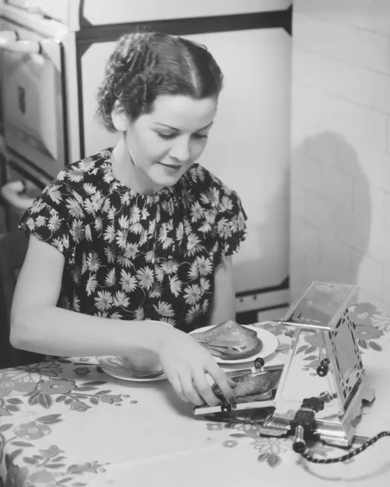 Framed Print : Young woman preparing toasts at kitchen table (B&W) Framed Print : Young woman preparing toasts at kitchen table (B&W)
