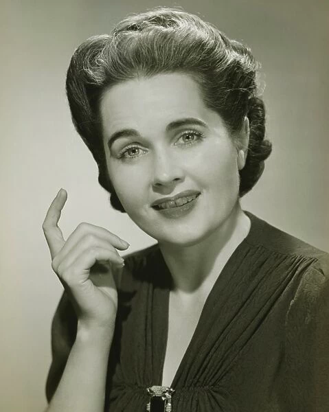 Young woman with raised index finger in studio, (B&W), portrait