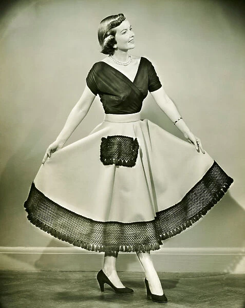 Young woman showing dress, posing in empty room, (B&W)