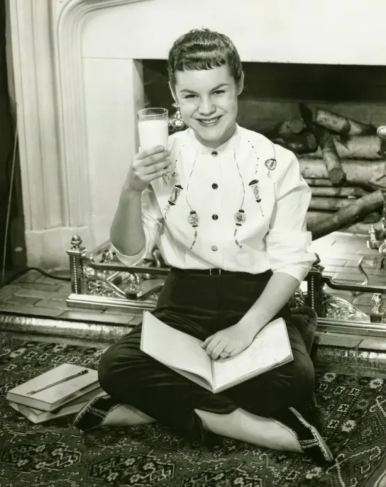 Framed Print : Young woman sitting by fireplace, holding glass of milk in raised hand, (B&W), portrait Framed Print : Young woman sitting by fireplace, holding glass of milk in raised hand, (B&W), portrait