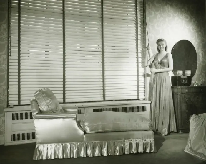 Framed Print : Young woman standing in living room, opening Venetian blinds, (B&W) Framed Print : Young woman standing in living room, opening Venetian blinds, (B&W)