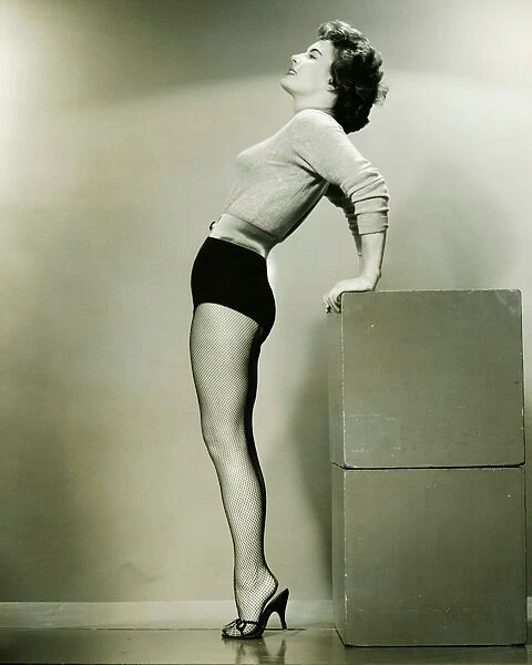 Young woman standing in studio, leaning backwards, (B&W)