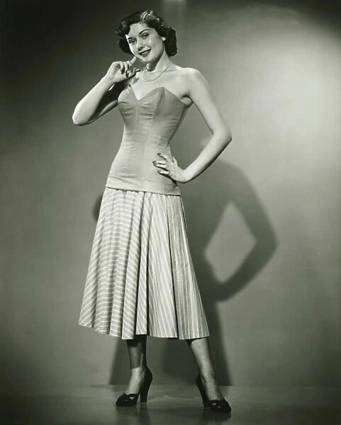 Young woman standing in studio, smiling, (B&W)