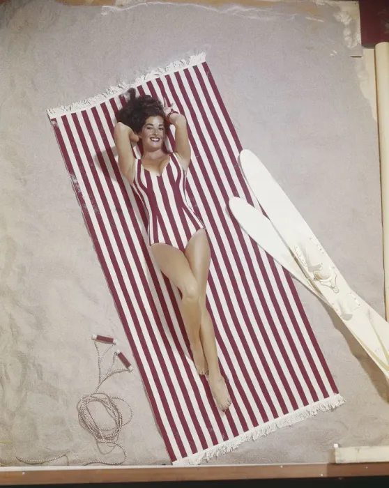 Framed Print : Young woman in striped swimwear lying on striped blanket Framed Print : Young woman in striped swimwear lying on striped blanket