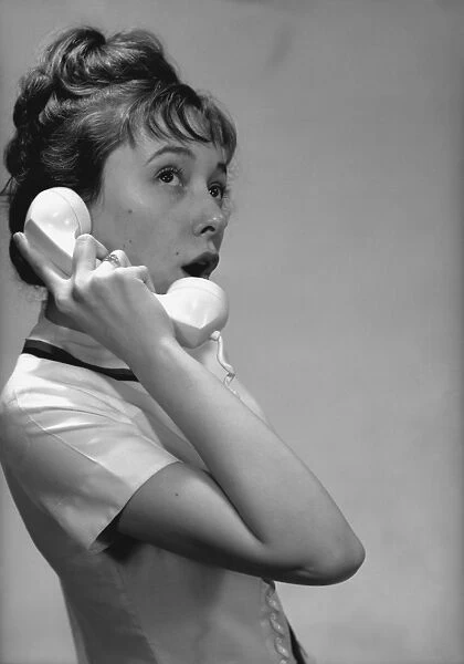 Young woman talking on phone in studio, (B&W)