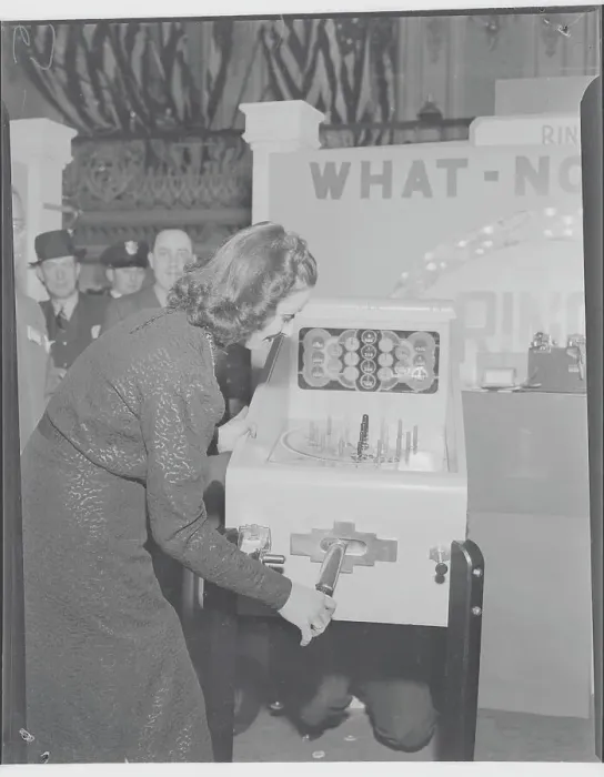Framed Print : Young Woman Testing Coin Machinery for Game at Exhibit Framed Print : Young Woman Testing Coin Machinery for Game at Exhibit