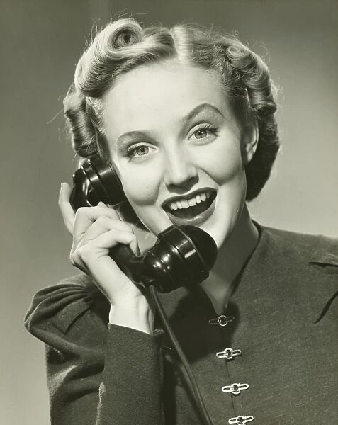 Young woman using phone, smiling, (B&W), portrait